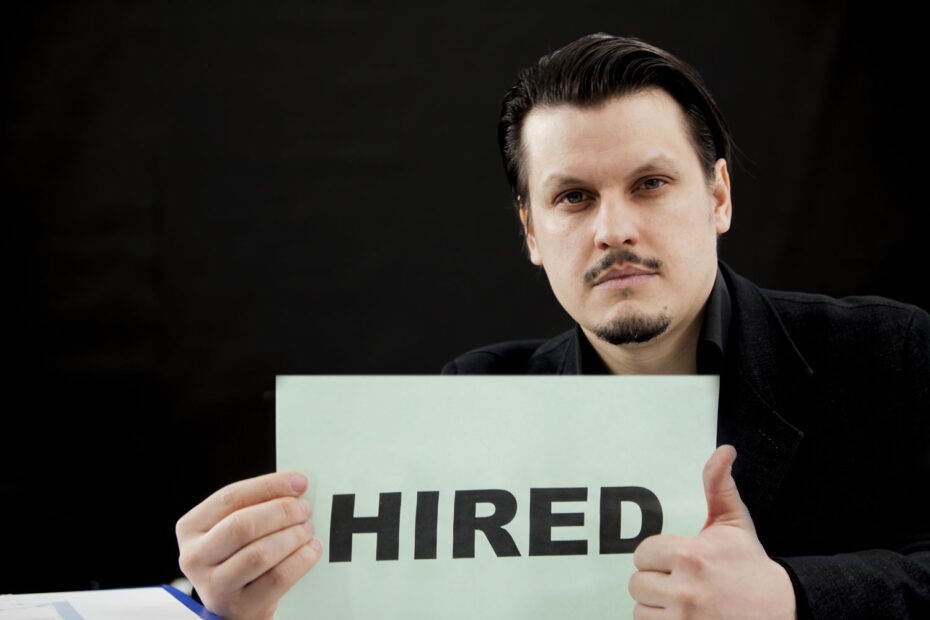 Man holding a sign that says Hired